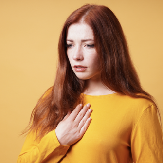 woman holding her chest due to heartburn