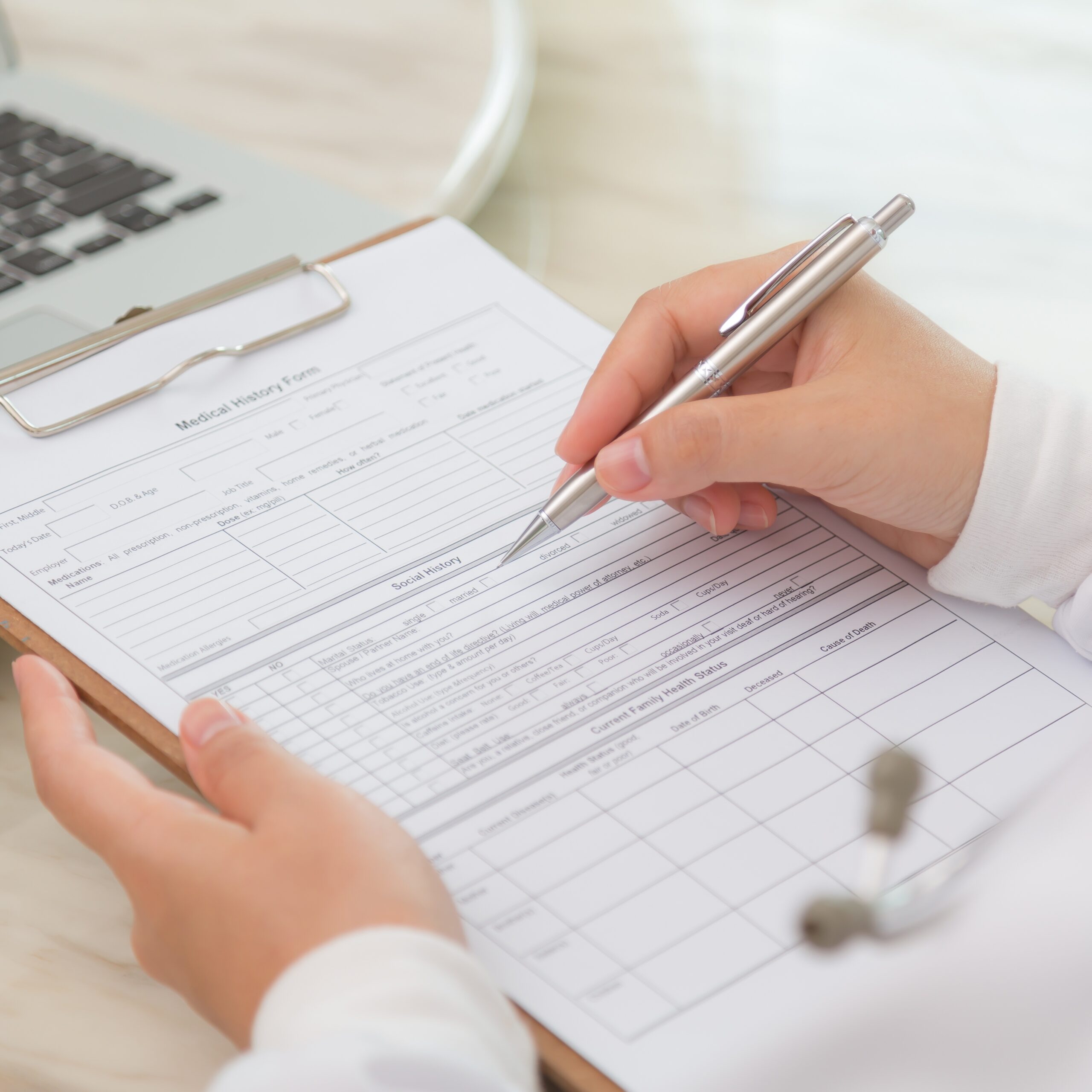 Close up of a GP using a clipboard and pen