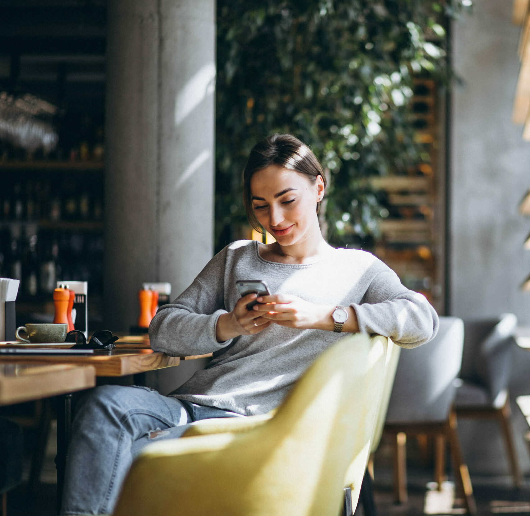 Woman sitting in a cafe drinking coffee and looking at her mobile phone