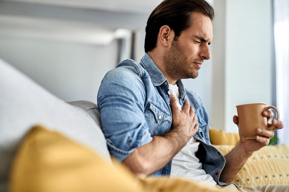 Young man with acid reflux and holding his chest in pain