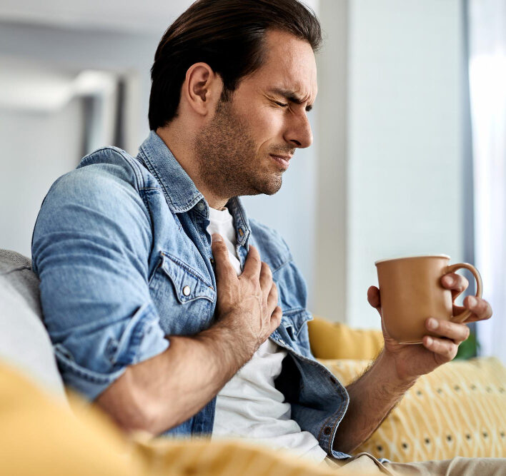 Young man with acid reflux and holding his chest in pain